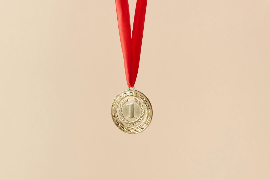 A gold medal hanging from a red ribbon